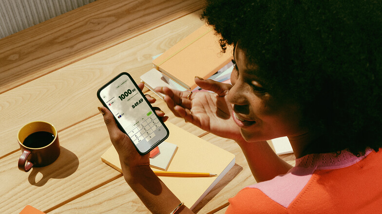 A person sat down with a coffee using the Wise app on their phone.